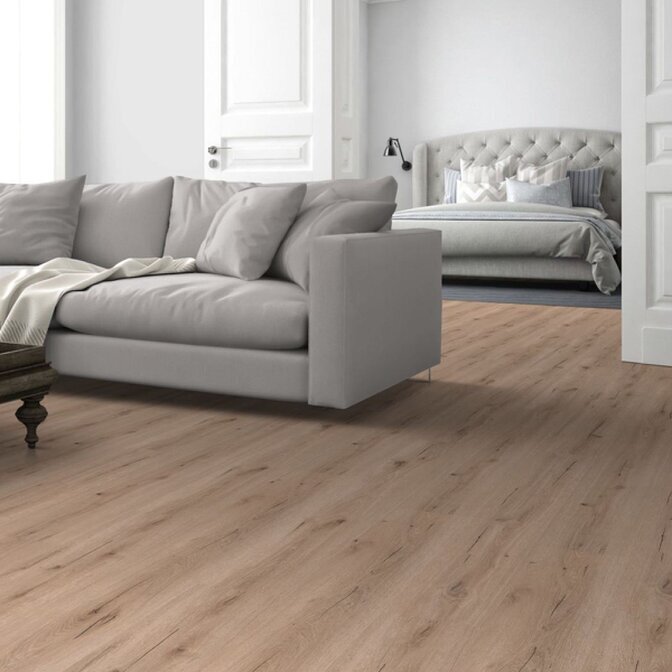 Unser Premium-Vinyl Raumbild eines beigen Klick-Vinyls in Holzoptik in einem Wohnbereich. Zu erkennen ist eine graue couch und im Hintergrund ein Schlafzimmer mit einem grauen Bett
